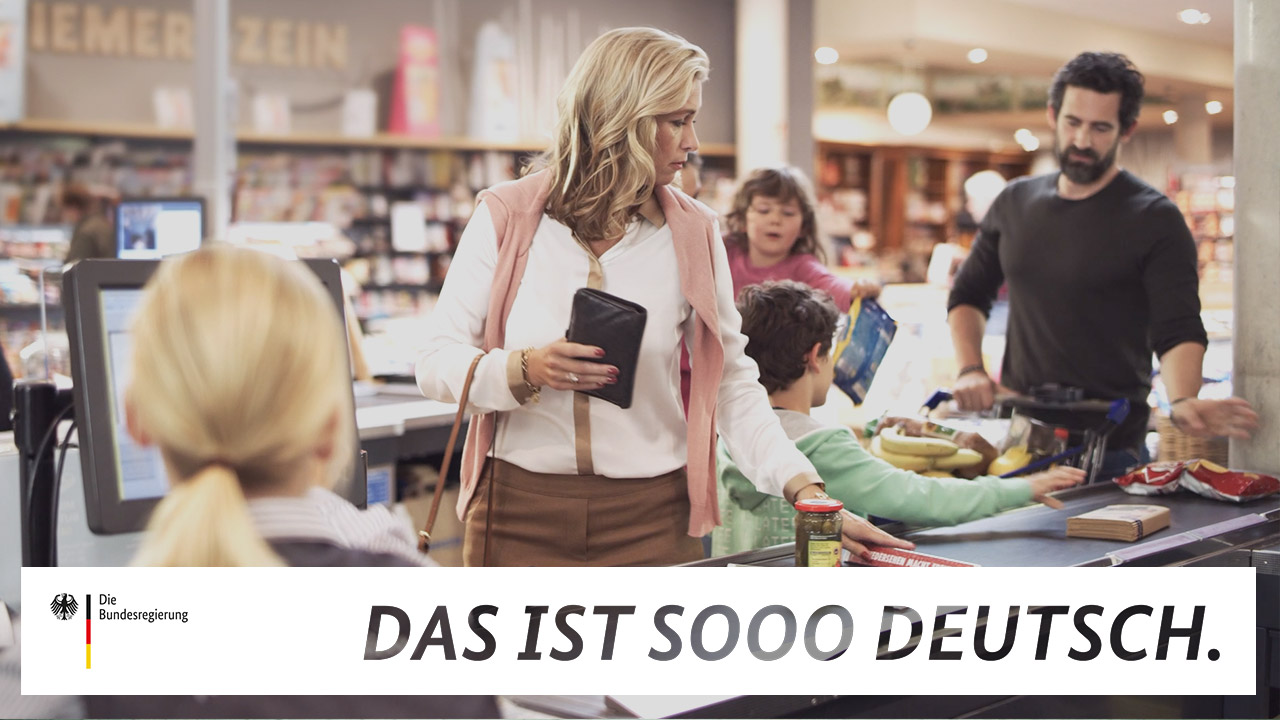 Ein Supermarkt mit Kunden, die Warentrenner auf das Kassenband legen, in einem Video der Reihe "Das ist sooo deutsch."
