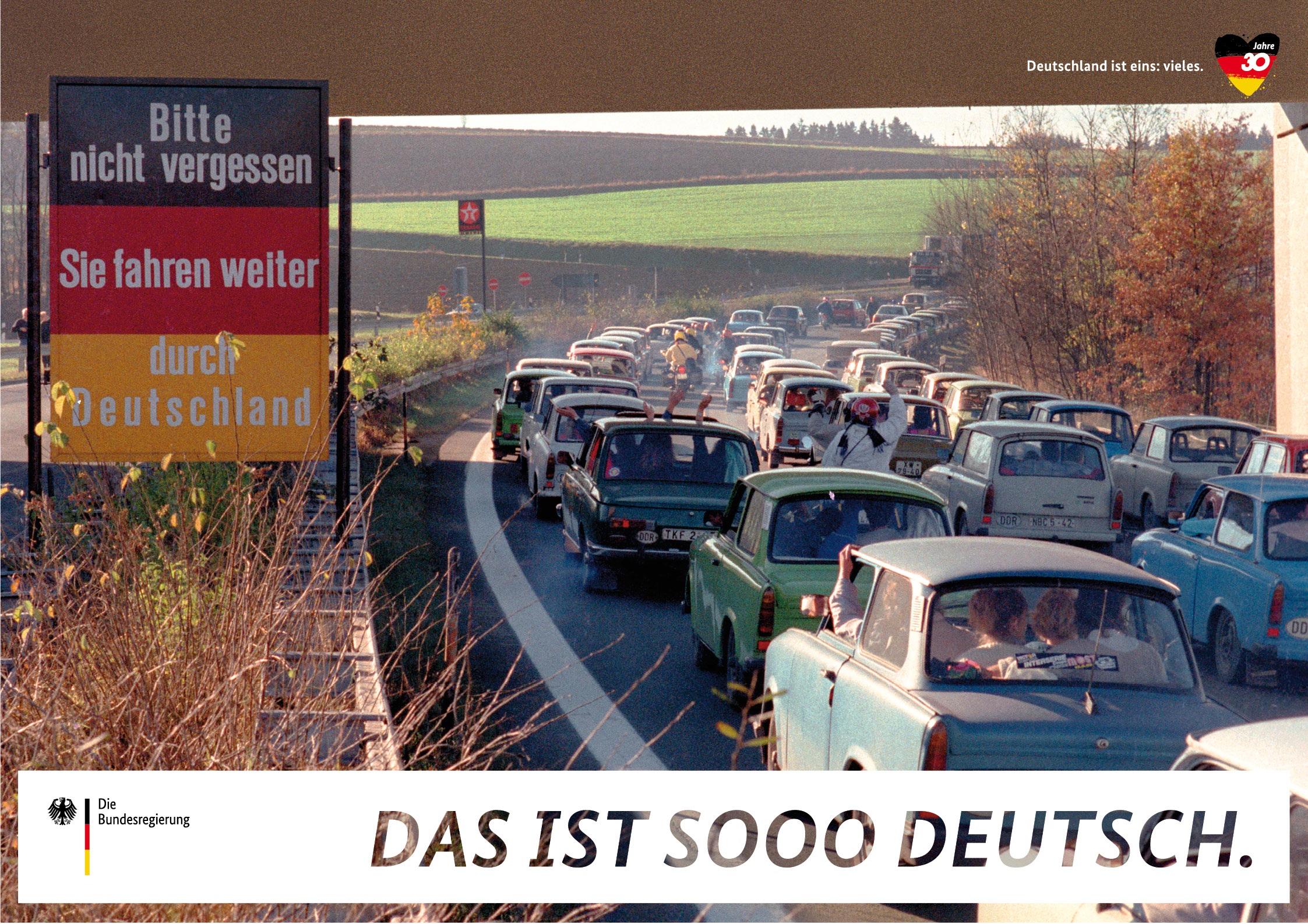 Ein Stau von Trabis auf einer Autobahn an der geöffneten innerdeutschen Grenze auf einem Plakat der Kampagne "Deutschland ist eins: vieles".